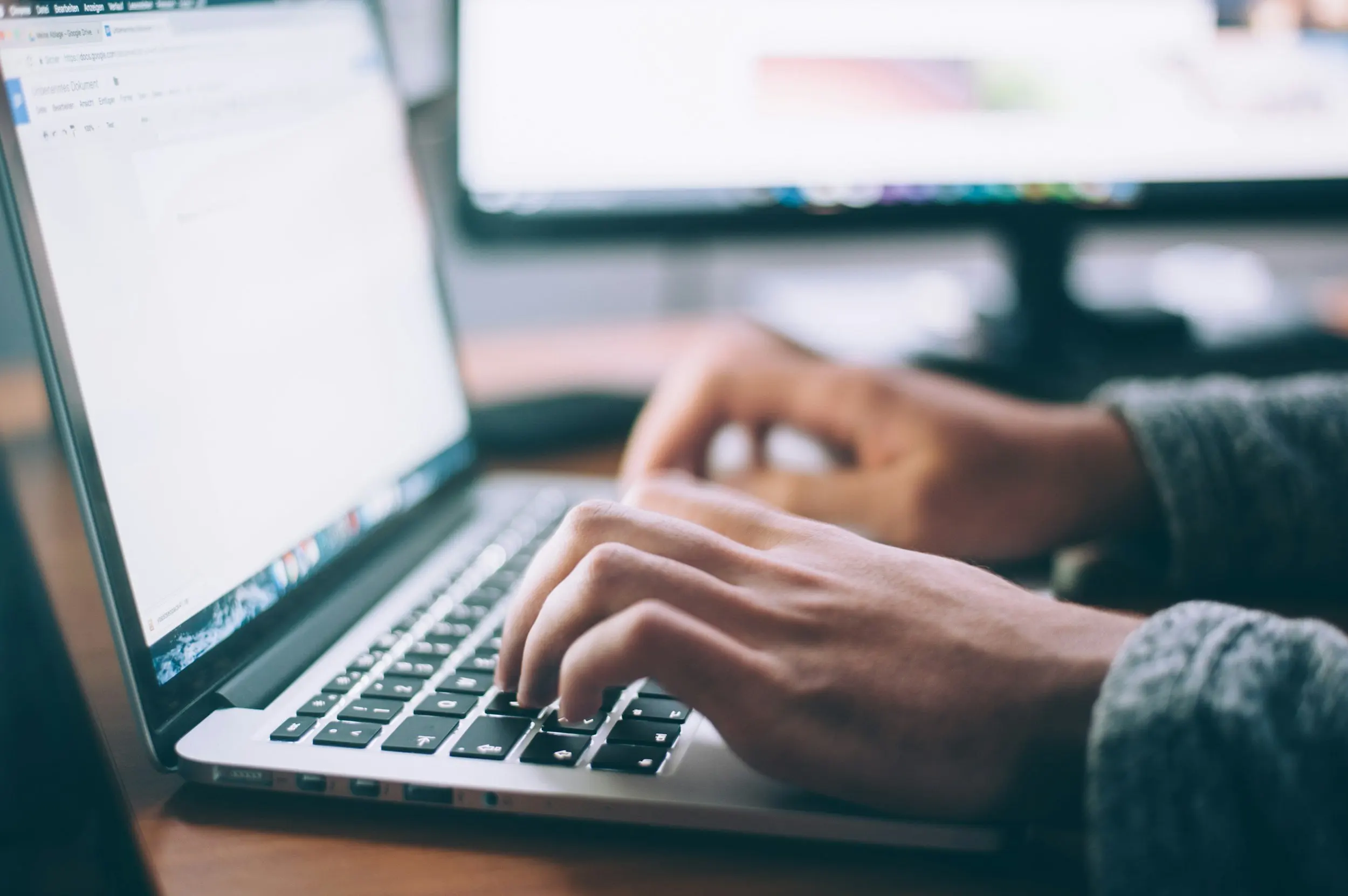 Close-up of an open laptop with hands typing, symbolising academic work or digital productivity.